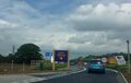A purple sign saying 'Happy travels, come back soon'.